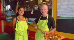 Two pizza makers holding a pizza.