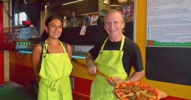 Two pizza makers holding a pizza.