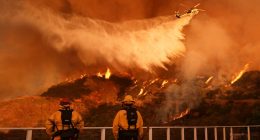 Firefighters watch a helicopter drop water on the Palisades Fire in Mandeville Canyon in Los Angeles, Jan. 11, 2025. (AP Photo/Jae C. Hong, File)