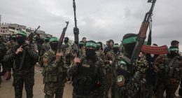 Hamas fighters carrying rifles at a hostage handover in Gaza.