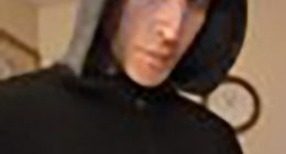 Close-up of a person wearing a dark hooded sweatshirt.