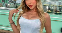 Portrait of a young woman in a light blue corset top and white pants.