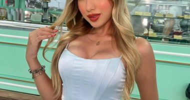Portrait of a young woman in a light blue corset top and white pants.