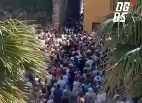 Large crowd of tourists overwhelming a narrow street in Sirmione.