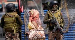 Indian soldiers stand guard as a woman walks in a market in Srinagar