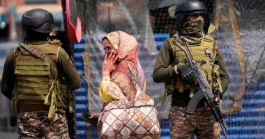 Indian soldiers stand guard as a woman walks in a market in Srinagar