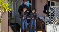 Police officer with two children outside a house.