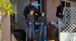 Police officer with two children outside a house.