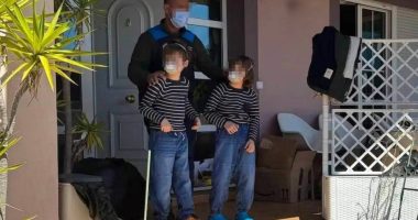 Police officer with two children outside a house.