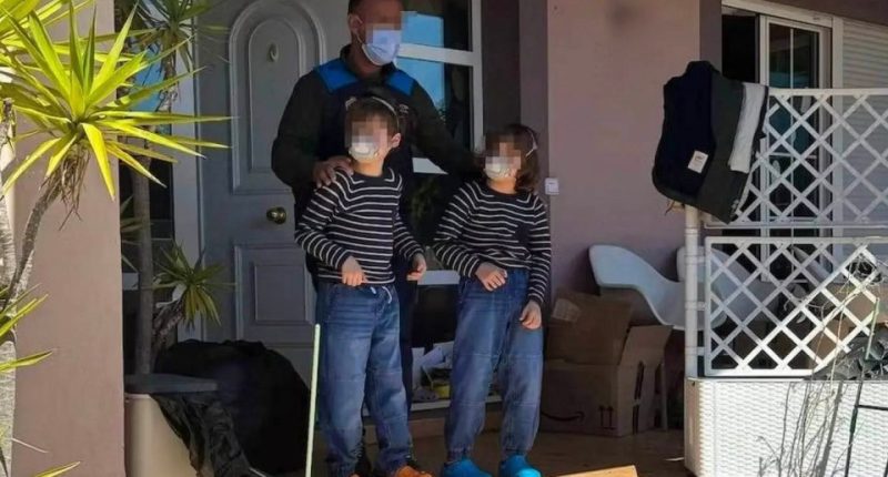 Police officer with two children outside a house.