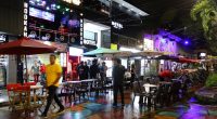 Night scene in Medellin, Colombia, showing tourists at outdoor cafes and hookah bars.