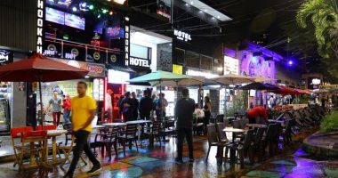 Night scene in Medellin, Colombia, showing tourists at outdoor cafes and hookah bars.