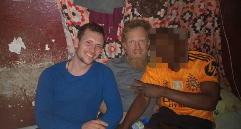Photo of three men sitting together in a prison cell.