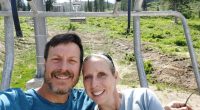A smiling couple sits on a chairlift.