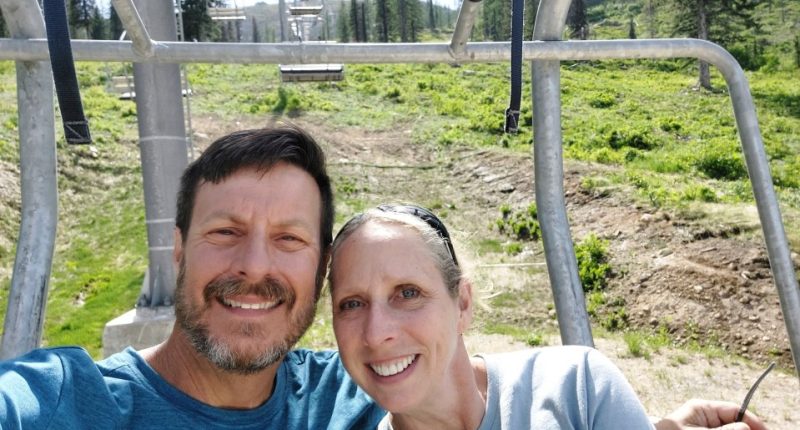 A smiling couple sits on a chairlift.