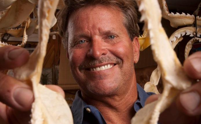 A man holding a large shark jaw.