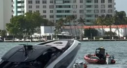 A luxury yacht partially submerged in the water near a high-rise building.