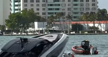 A luxury yacht partially submerged in the water near a high-rise building.
