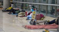 People sleeping on the floor of an airport terminal.