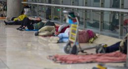 People sleeping on the floor of an airport terminal.