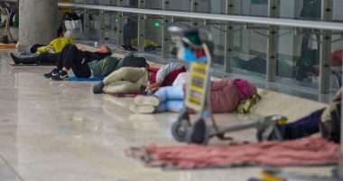 People sleeping on the floor of an airport terminal.