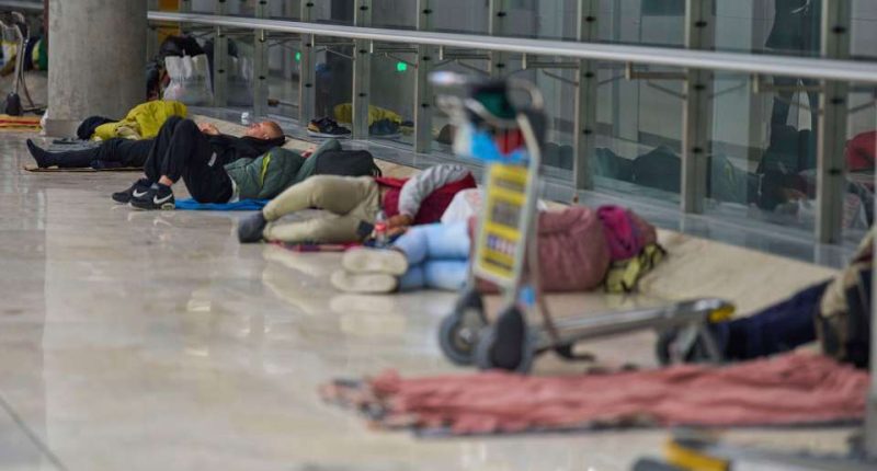 People sleeping on the floor of an airport terminal.