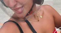 Woman wearing a motorcycle helmet and red bikini top sticking her tongue out.