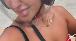 Woman wearing a motorcycle helmet and red bikini top sticking her tongue out.
