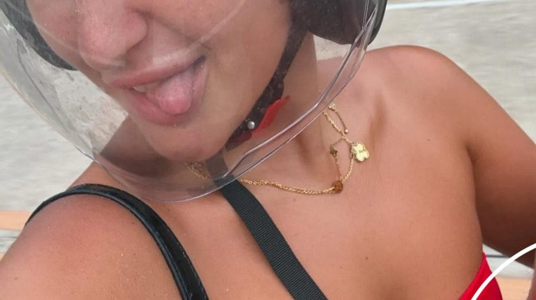 Woman wearing a motorcycle helmet and red bikini top sticking her tongue out.