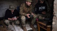 Ukrainian drone operators operating equipment in a makeshift command post.