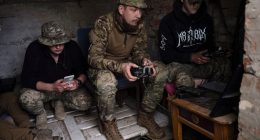 Ukrainian drone operators operating equipment in a makeshift command post.