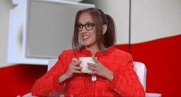 Kat Timpf in a red jacket holding a mug.