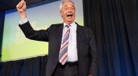 Nigel Farage celebrating on stage after Reform UK's election win.