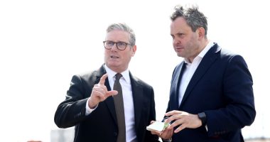 Two men in suits discussing something, one pointing.