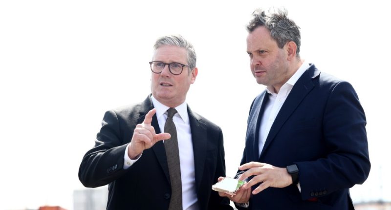Two men in suits discussing something, one pointing.