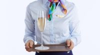 Flight attendant holding a tray with a glass of champagne.