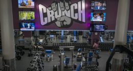 People wearing masks work out at a Crunch Fitness gym.