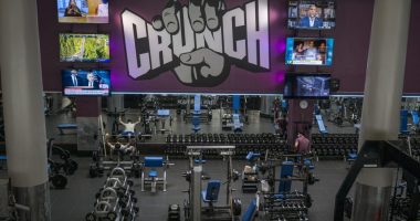 People wearing masks work out at a Crunch Fitness gym.