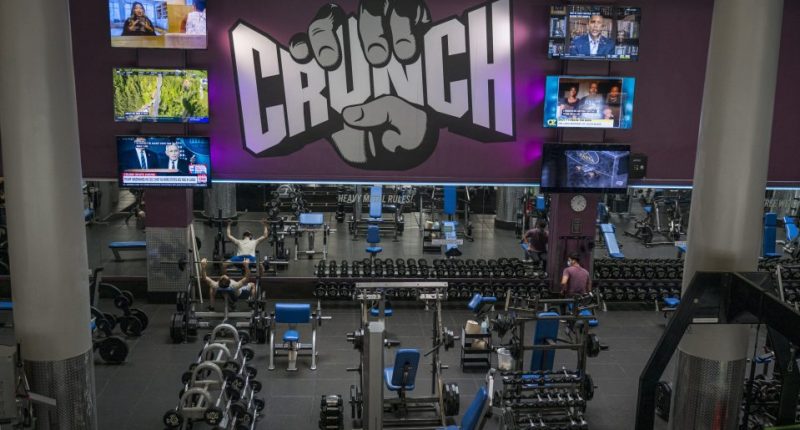 People wearing masks work out at a Crunch Fitness gym.