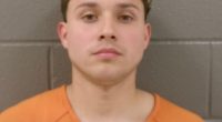 Mugshot of a young man in an orange shirt.