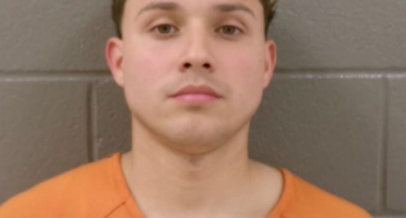 Mugshot of a young man in an orange shirt.