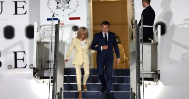 Emmanuel and Brigitte Macron disembarking from a plane.