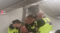 Police officers arresting a disruptive passenger on an airplane.