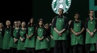 Starbucks baristas stand on stage, March 20, 2019, during an annual shareholders meeting in Seattle. (AP Photo/Ted S. Warren, file)