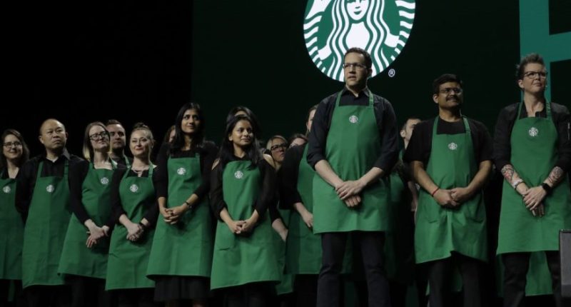 Starbucks baristas stand on stage, March 20, 2019, during an annual shareholders meeting in Seattle. (AP Photo/Ted S. Warren, file)