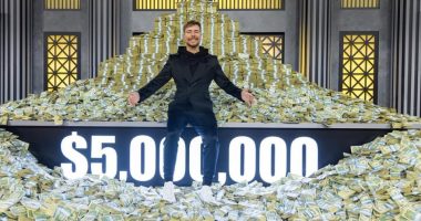 Man sitting on a large pile of money; $5,000,000 displayed.