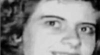 Black and white photo of a smiling woman with curly hair.