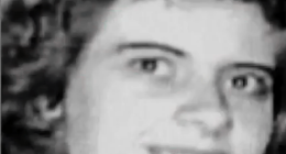 Black and white photo of a smiling woman with curly hair.