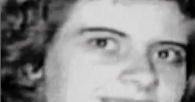 Black and white photo of a smiling woman with curly hair.
