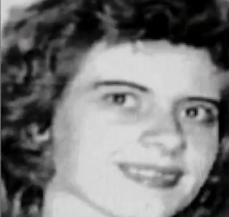 Black and white photo of a smiling woman with curly hair.